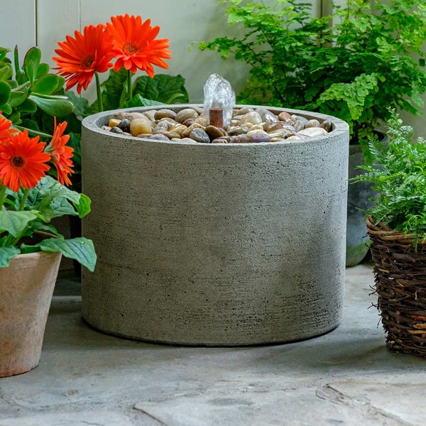 Campania International Salinas Pebble Fountain, Low on concrete beside orange flowers