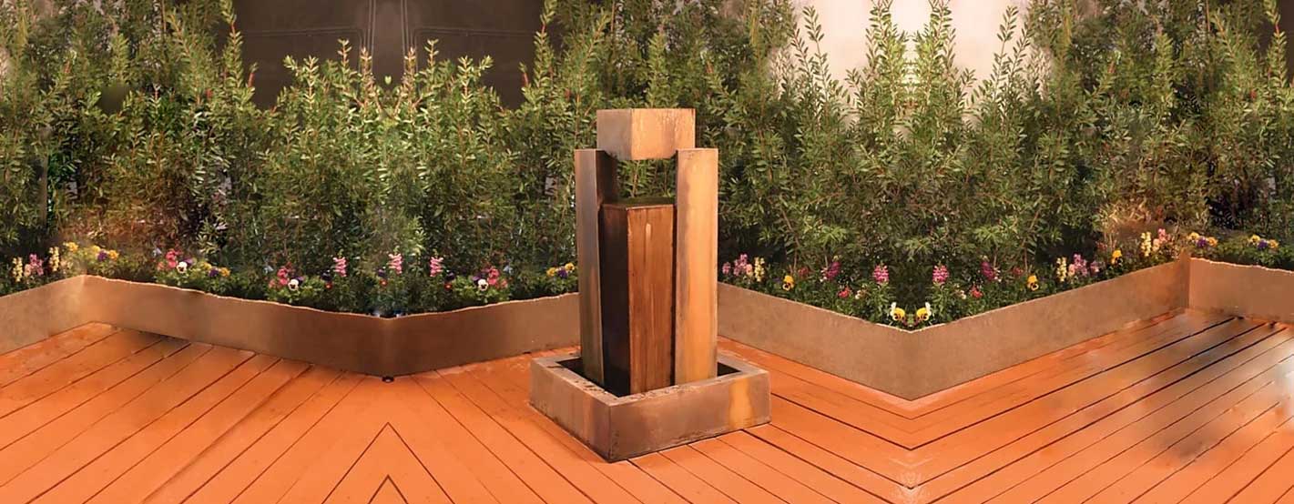 Rocket Fountain on wooden floor against green plants with flowers
