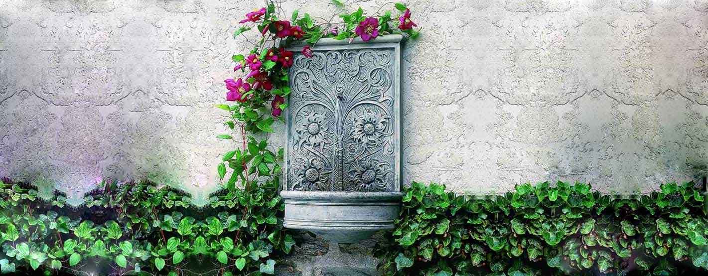 Sussex Wall Fountain with pink flowers against white wall