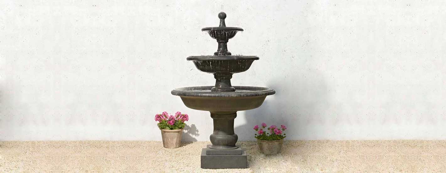 Vicobello Fountain in action beside pink flowers in pot