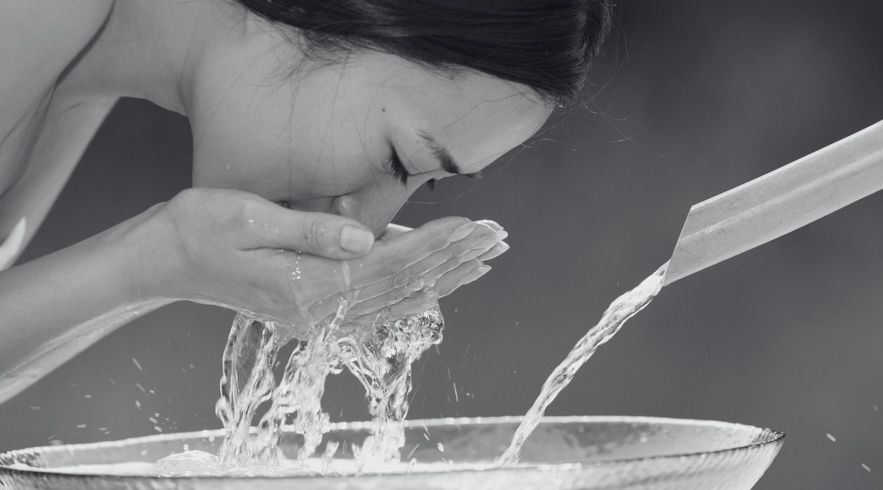 Black and white photo of woman washing her face with water