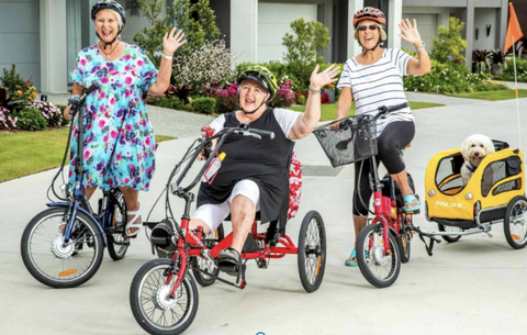 3 happy ladies riding their electric bikes and trikes with their dogs