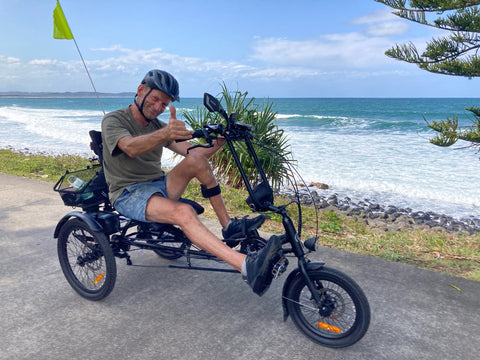 roger riding his electric trike at the beach pulling thumbs up