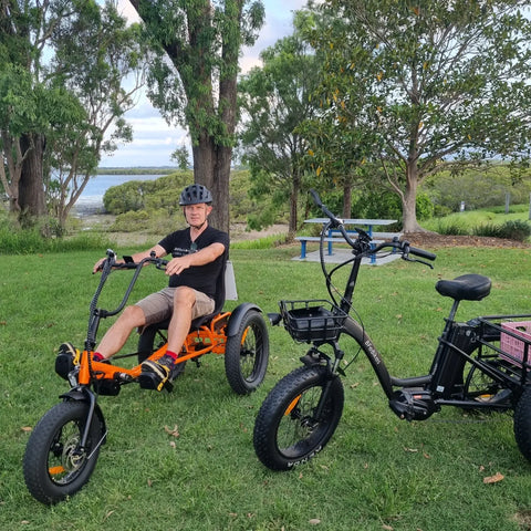 man sitting in orange trike while next to black trike