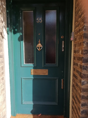 Worn out wooden front door with tarnished door furniture and old locks