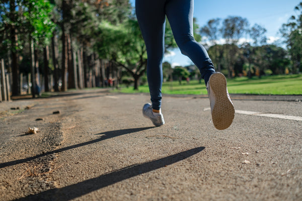woman's legs running on a path in the park wearing running shoes