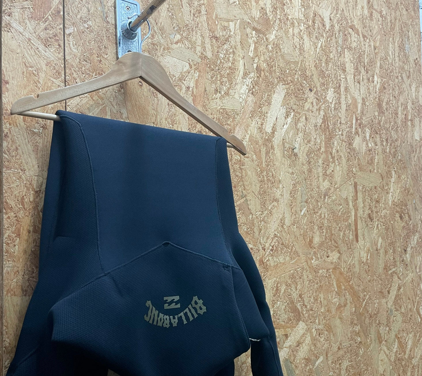 Wetsuit hung off lower rung of hanger (Wetsuit Care Guide)