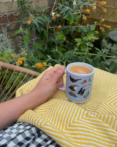 Under-a-blanket-with-bird-print-mug-of-tea-outside