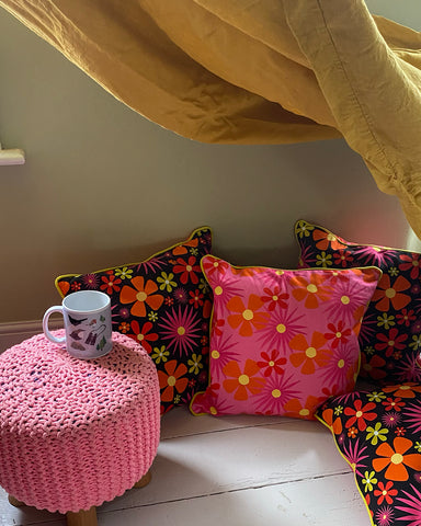 Pink-flower-print-cushions-on-a-white-wooden-floor-under-a-mustard-yellow-blanket-fort
