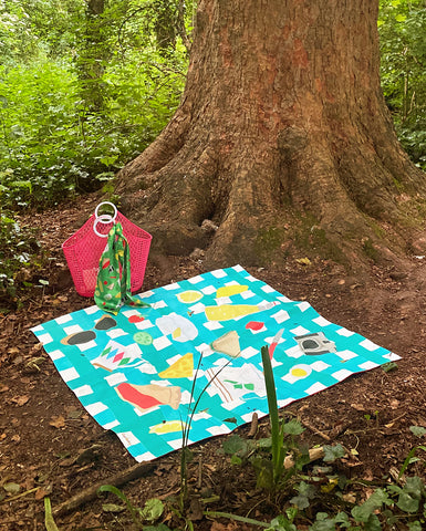 Colourful-picnic-blanket-in-front-of-a-tree-with-a-pink-basket