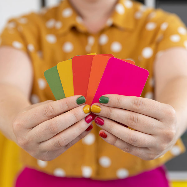 Hands-holding-colour-swatches-in-green-yellow-red-orange-and-pink