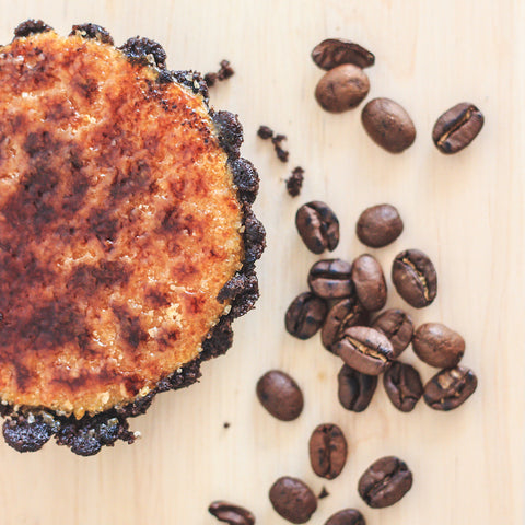 Coffee flavoured creme brulee with coffee beans sprinkled next to it.