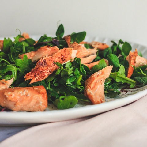 Plate with salmon pieces and green salad.