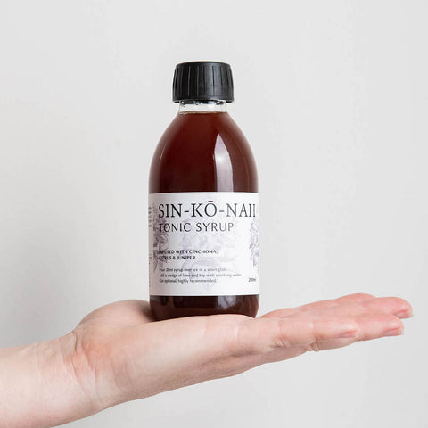 A hand holding a bottle of sinkonah tonic syrup.