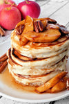 stack of pancakes topped with apple slices and pecans