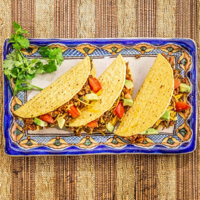 Three hard shell tacos on a ceramic plate