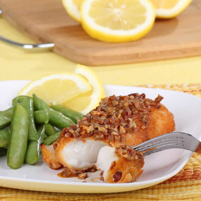Spicy pecan-crusted fish fry on plate with peas and lemon