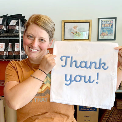 Jess in the shop holding up a sign that says Thank You!