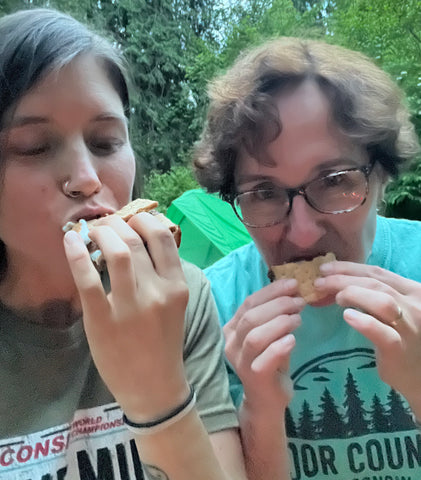 Selfie of two people eating s'mores outside