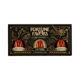 Black and gold sampler gift pack containing three 4 ounce cans of Fortune Favors candied pecans, one of each signature flavor.