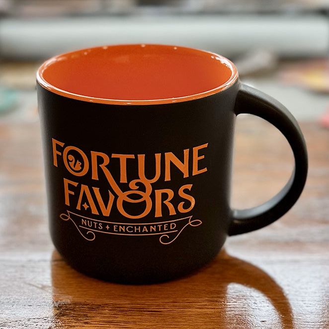 Empty orange and black Fortune Favors coffee mug.