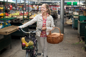woman on her bicycle shopping at a farmers market, for a greener lifestyle