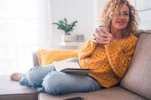 Woman relaxing and drinking tea and reading a book, tips to help manage stress.