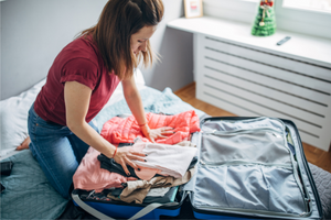 Woman packing suitcase - think ahead about how to stay healthy during travel.