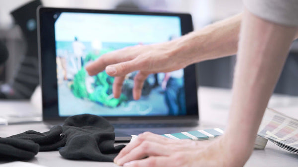 Man showing on a laptop his new developments about the performance socks of Teal made from ocean plastics and other plastics, designed in switzerland, made in portugal