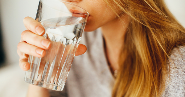 mujer bebiendo agua para hidratar su cuerpo