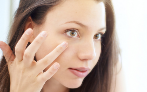 Mujer aplicando crema facial en el contorno de los ojos