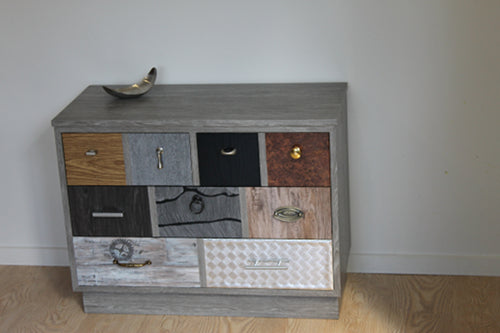 grey wood grain lowboy with every drawer front covered with various vinyls