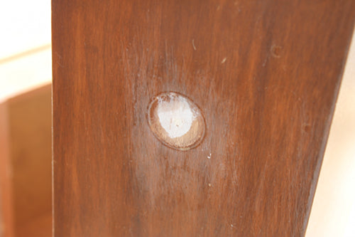 hole in wooden drawer front filled with white gap filler