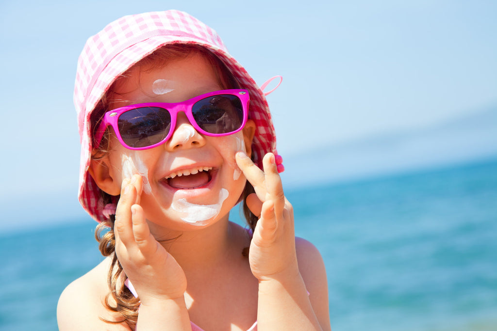 Child applying sun cream to her face