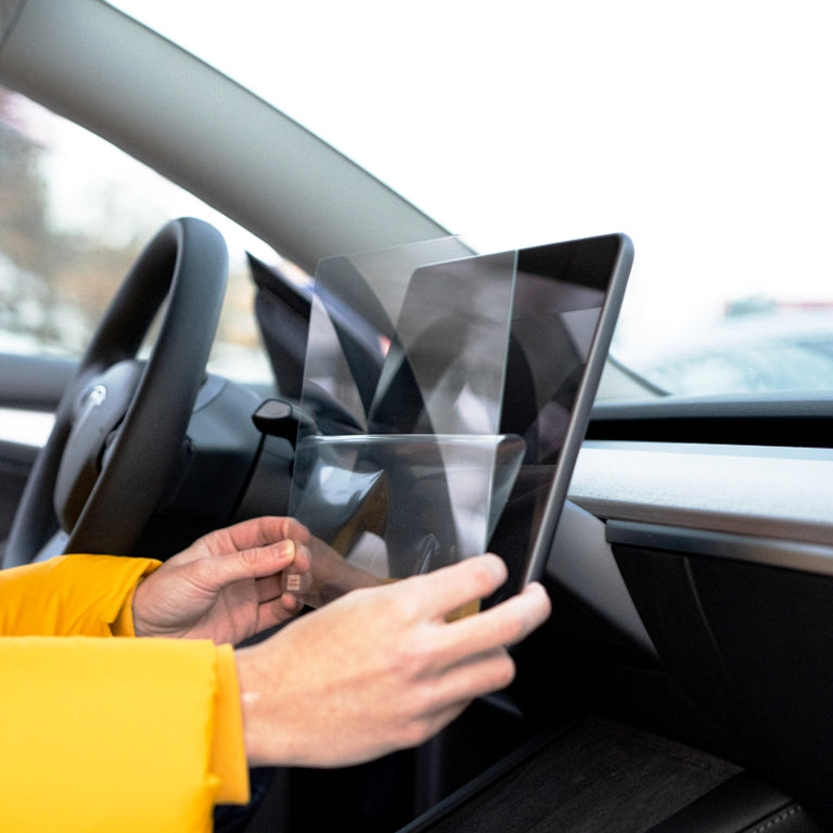 Person installing a screen protector on the LCD screen of a car