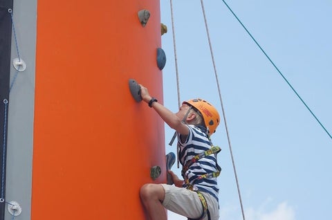 Rock climbing kid with al the proper equipment like helmet, harness and belay rope