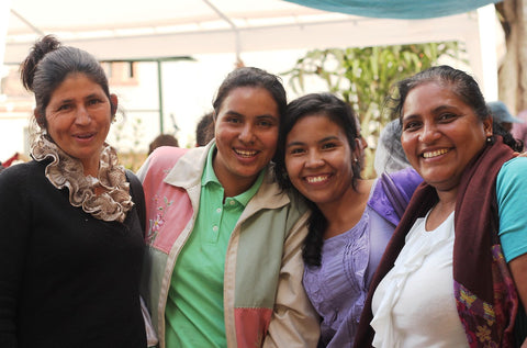 Four woman hugging each other and smiling towards the camera