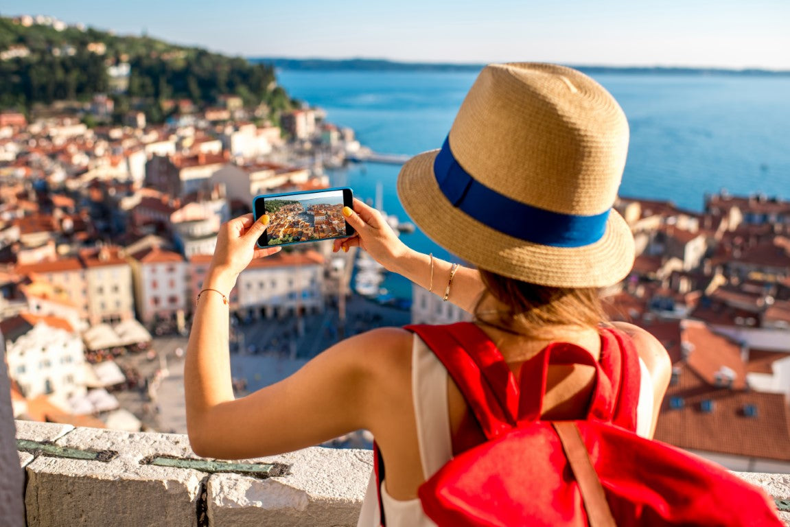 Young-female-traveller-with-red-backpack-and-photo-camera-enjoying-the-view-on-old-town.j