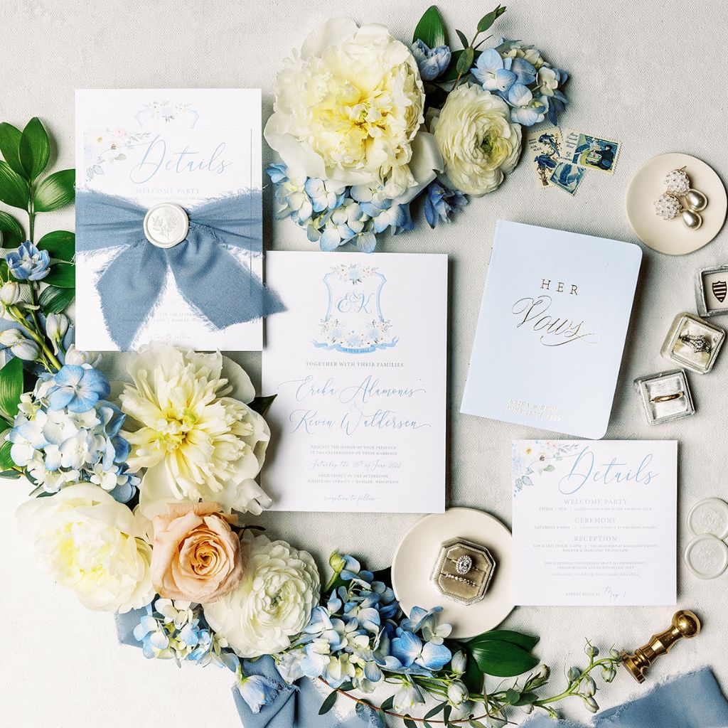 A flat lay photograph of a custom dusty blue wedding invitation suite