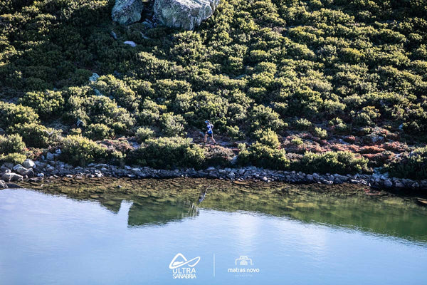 Lady running on a scenic trail with a lake and green area in an Ultra Sanabria race.