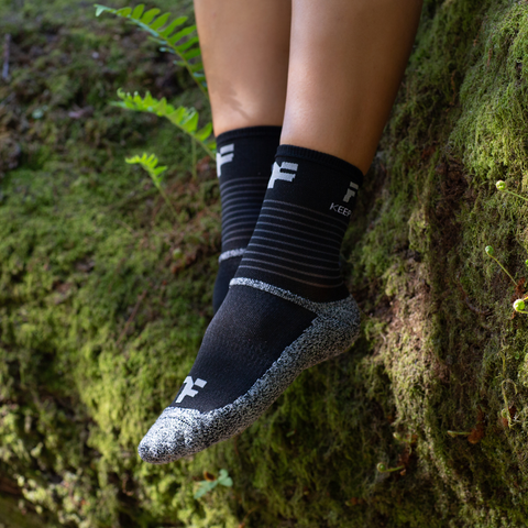 feet wearing the black Fyke Mid Sports Socks in a forest area.