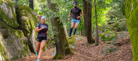 Man and woman trail running in a forest area wearing Fyke sportswear.