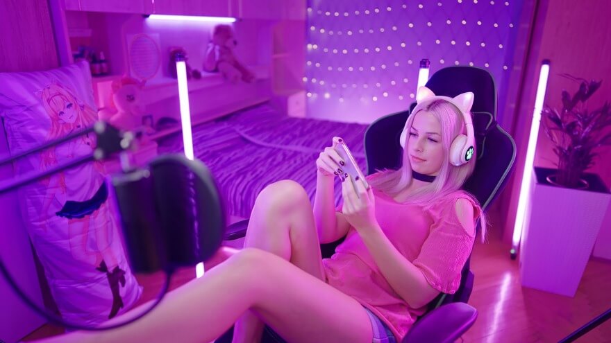 An egirl with her cute gaming headset is playing relaxed video games on her phone