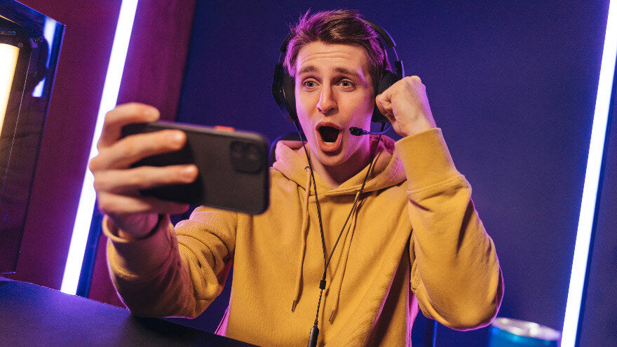 An happy competitive gamer on mobile is celebrating its victory