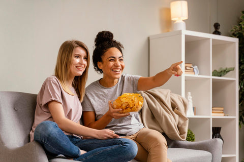 2 women on couch enjoying chips