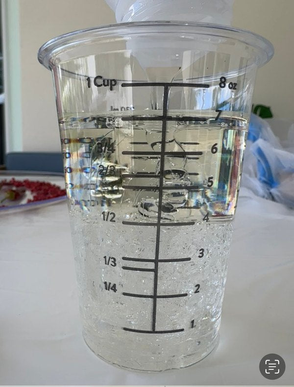 A measuring cup being filled with epoxy resin components for a resin batch.