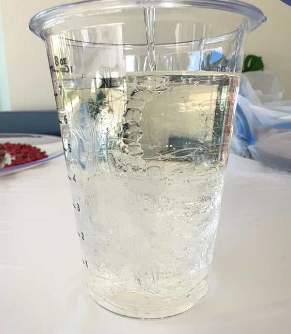 A mixing cup being topped off with the epoxy resin component prior to blending.