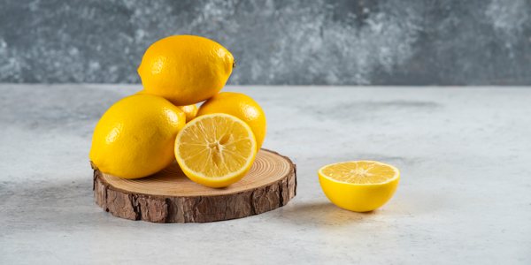 Lemons, some whole, some cut, resting on a countertop surface.