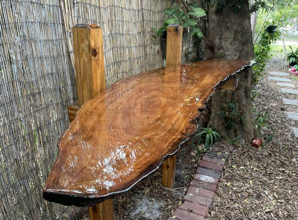 An outdoor live edge mounted wooden bar top.
