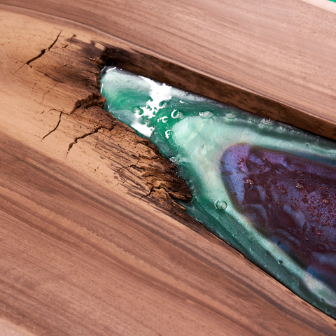 Pigmented epoxy resin flowing into a wooden river table vein